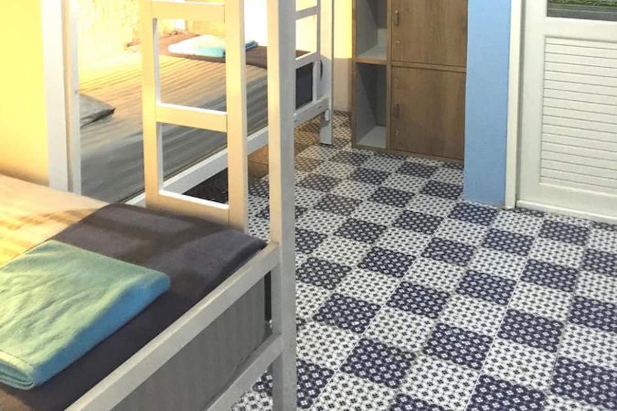 Une chambre de dortoir avec des lits superposés, une armoire en bois et un sol à motifs.