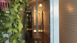Un pasillo con suelo de madera, una mesa con sillas y plantas colgantes.