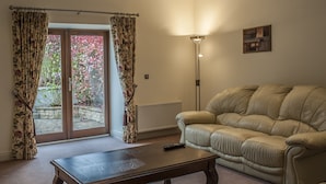 A living room with a sofa, a coffee table, and a floor lamp. - New Forest Golf Club Apartments (Tyrrellspass)