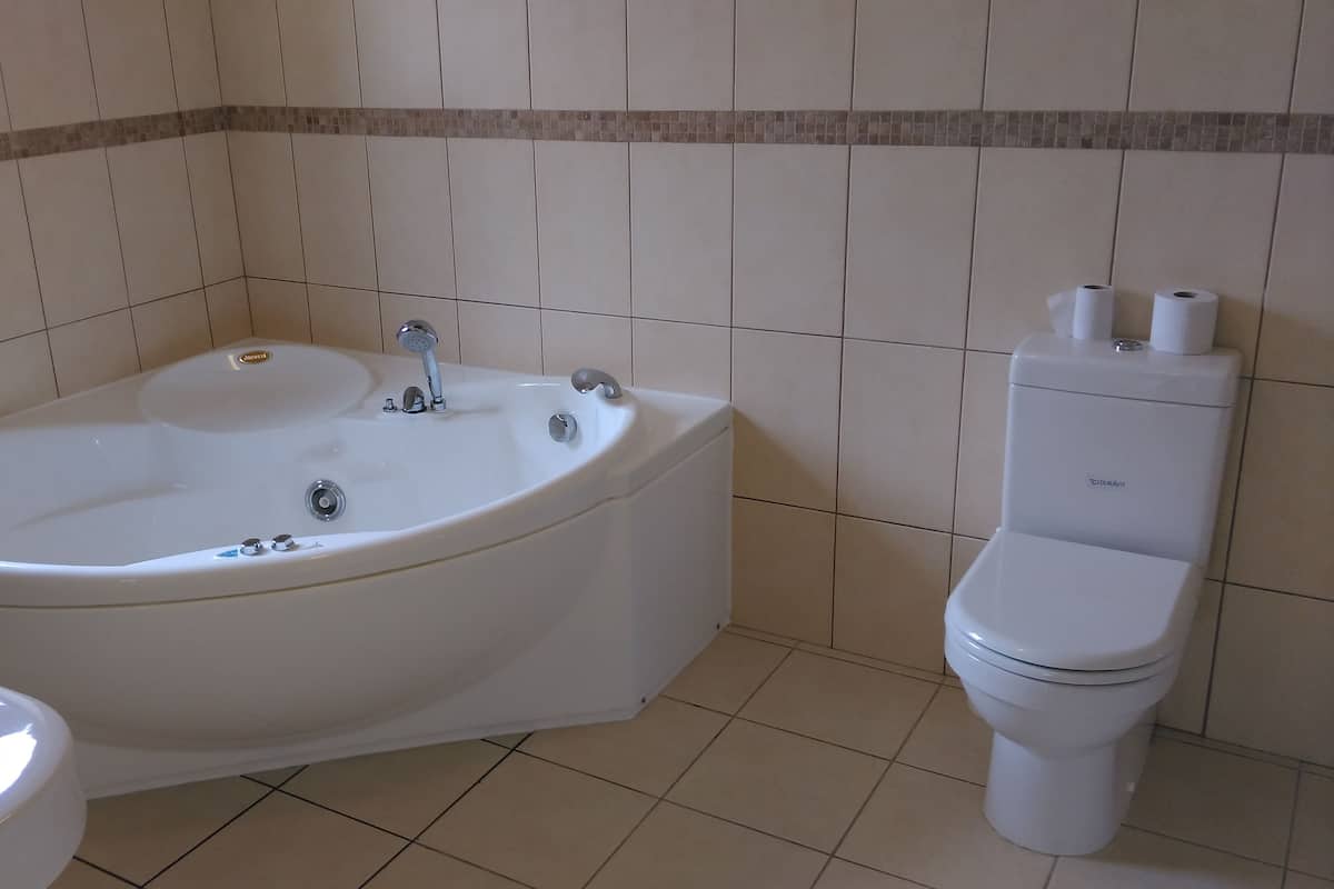 Une salle de bain avec une baignoire blanche, des toilettes et une fenêtre.