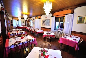 A restaurant with multiple tables, each set with white tablecloths and red napkins. - Albergo Ristorante Morandi (Valbondione)