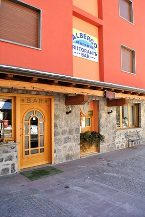 Un bâtiment à la façade en pierre et à la porte en bois portant l’inscription « BAR ».