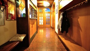 A corridor with wooden benches, a coat rack, and a door with glass panels. - Albergo Ristorante Morandi (Valbondione)