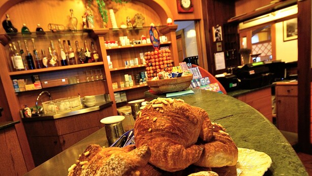 A bakery counter with pastries and a display of bottles. - Albergo Ristorante Morandi (Valbondione)