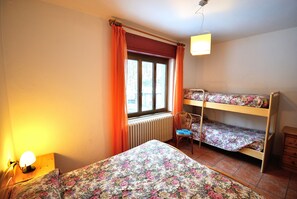 Une pièce comprenant un lit, une chaise, une fenêtre avec des rideaux, un radiateur et un lit superposé.