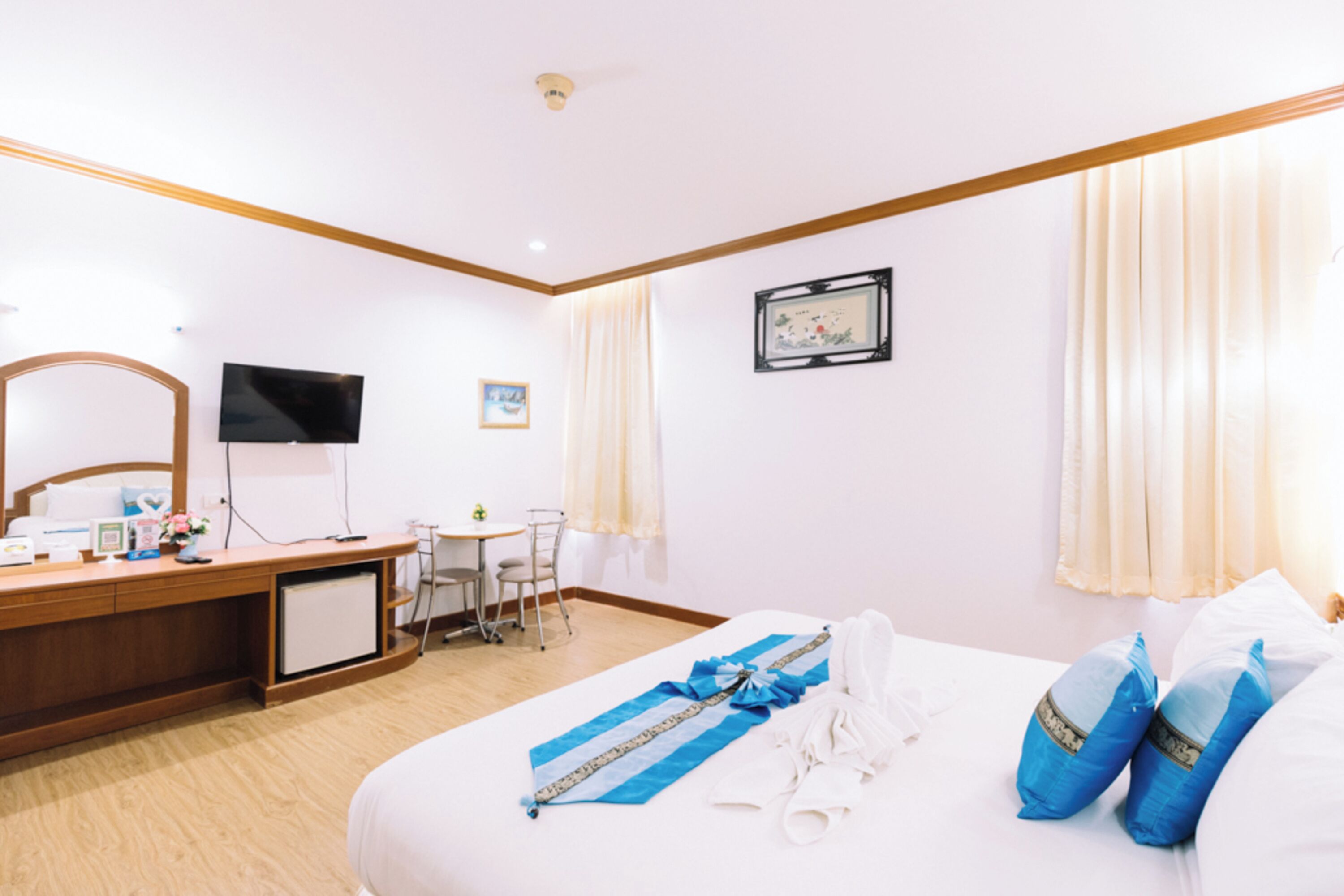 Una habitación de hotel con cama, escritorio, televisor y una pequeña mesa.