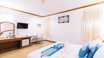 Una habitación de hotel con cama, escritorio, televisor y una pequeña mesa.