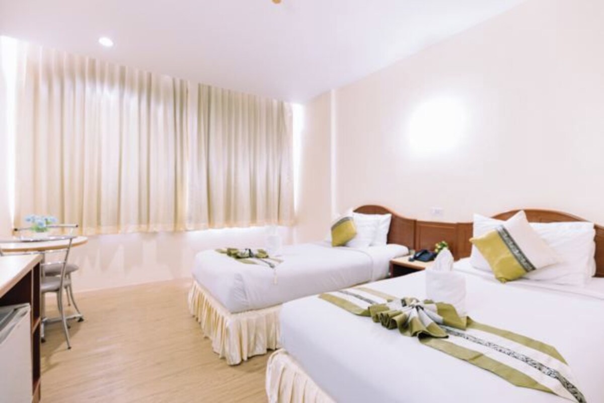 A hotel room with two beds, a desk, and a chair.