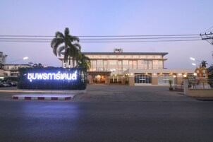 Entrada de hotel con un letrero iluminado, una palmera y una fachada de edificio bien iluminada.