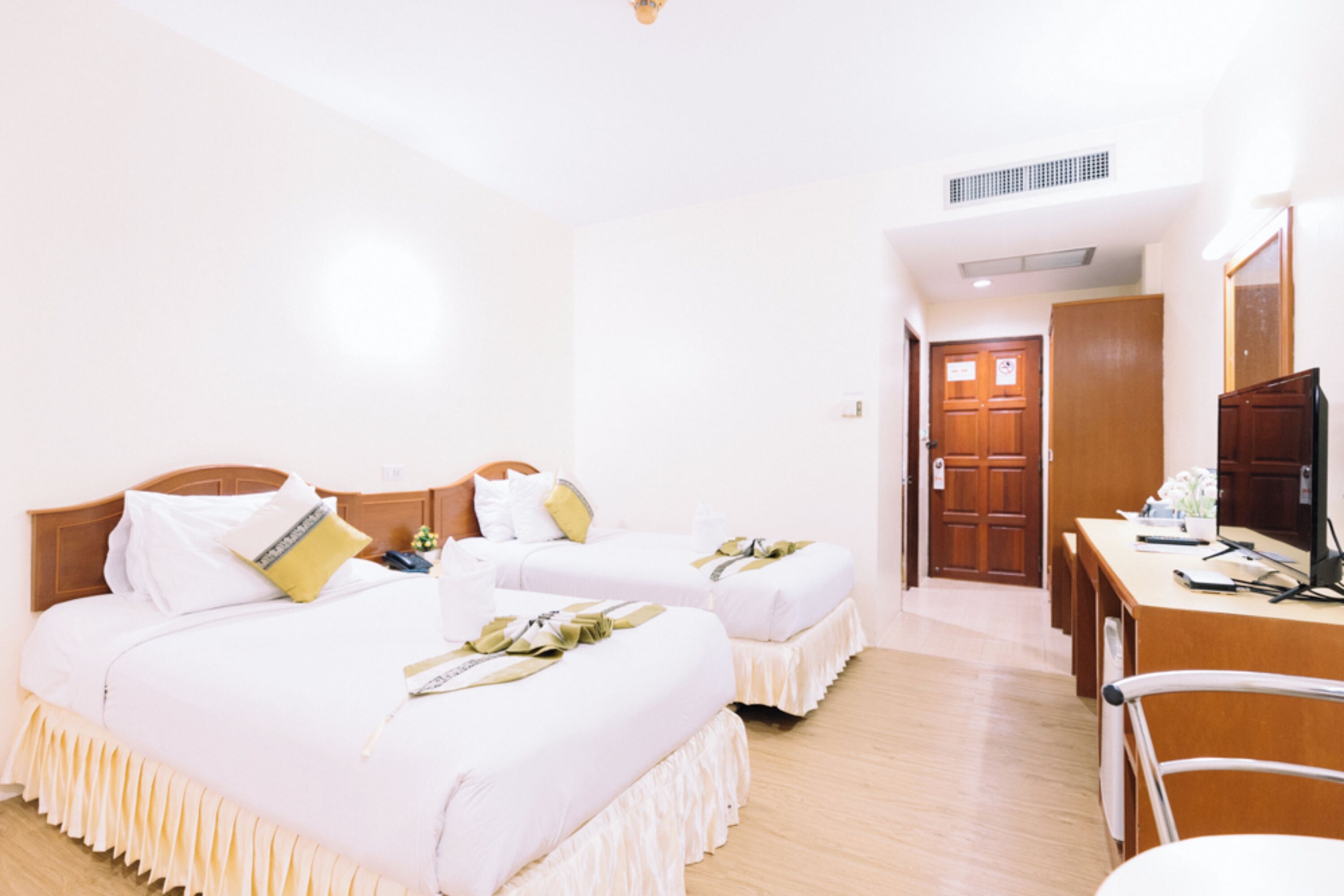 Habitación de hotel con dos camas, un escritorio y un televisor.