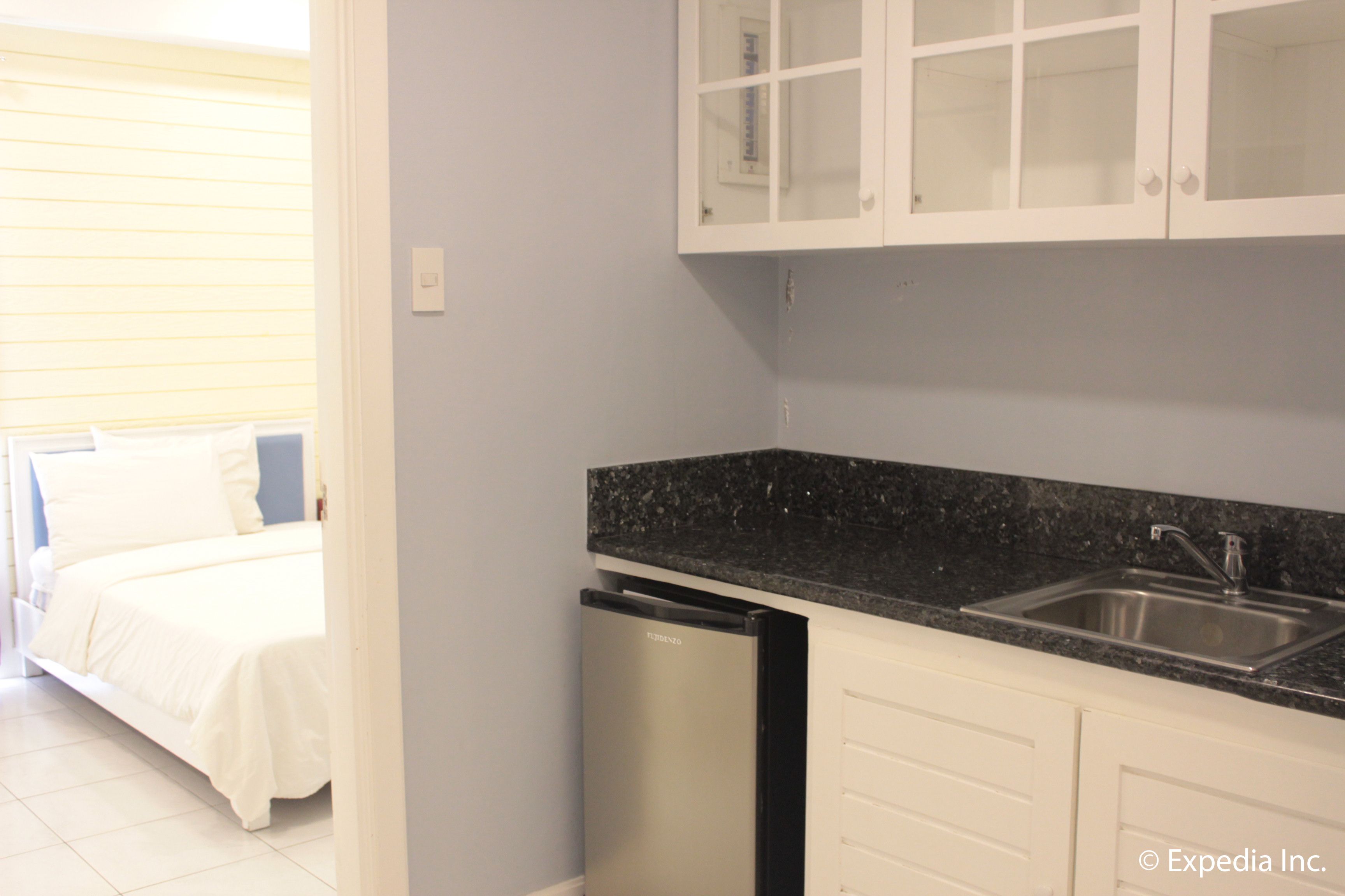 A compact kitchen with white cabinets, a black countertop, and a built-in dishwasher.
