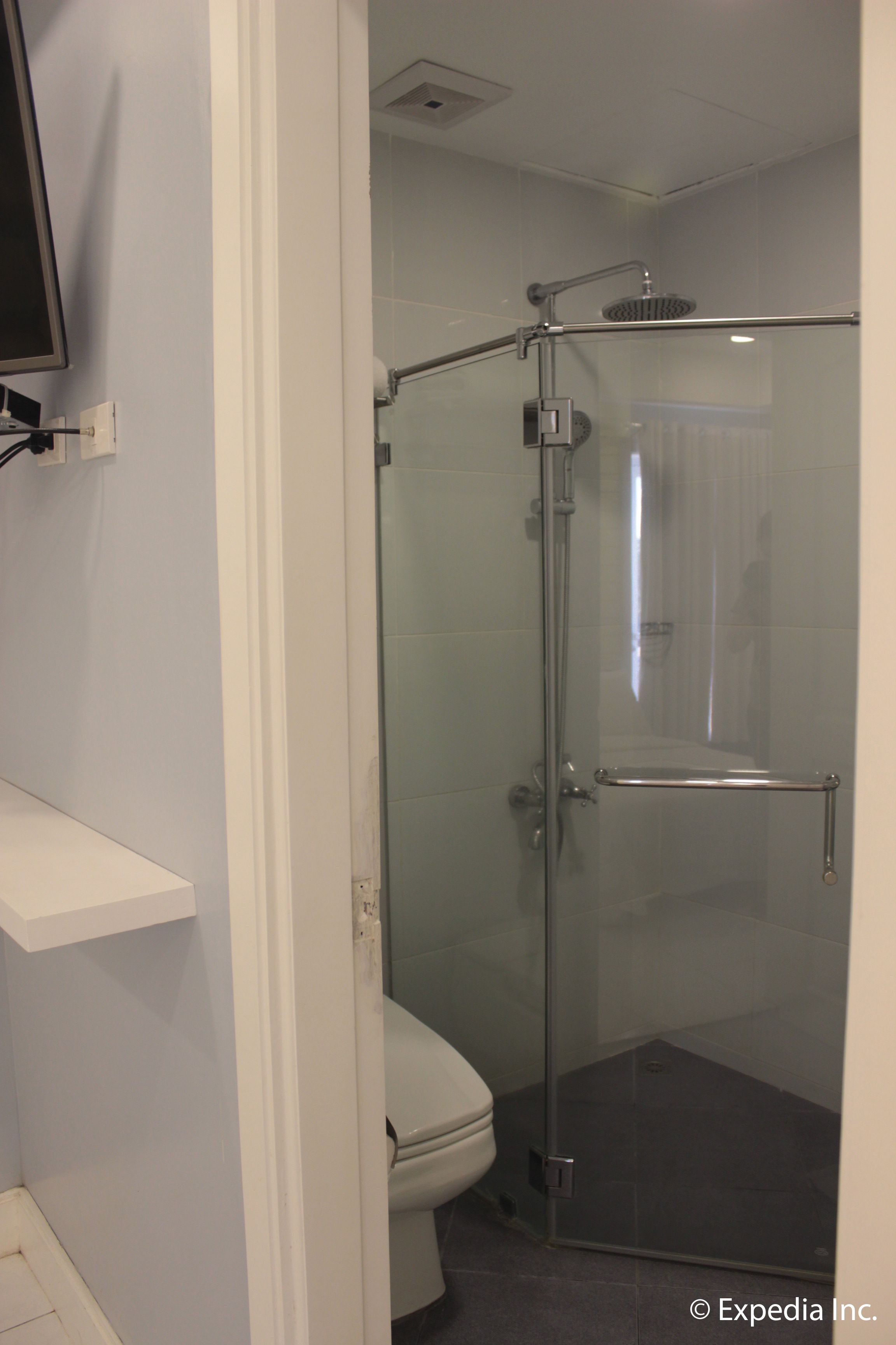 A bathroom with a glass-enclosed shower, a toilet, and a white sink.
