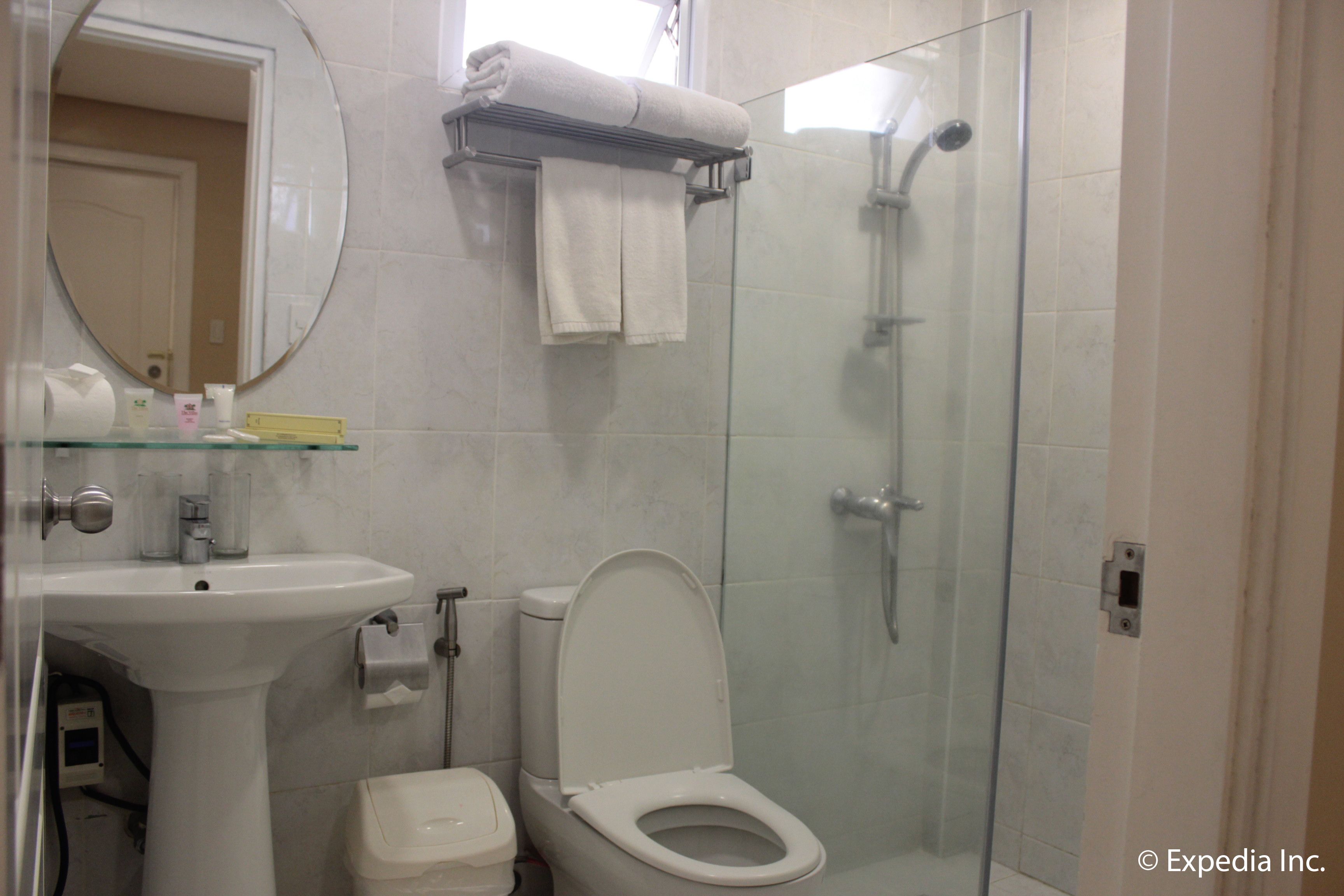 A bathroom with a glass-enclosed shower, a white sink, and a toilet.