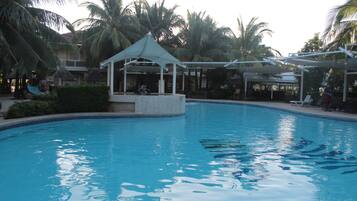 Relax by the serene pool surrounded by lush greenery and a shaded pavilion.