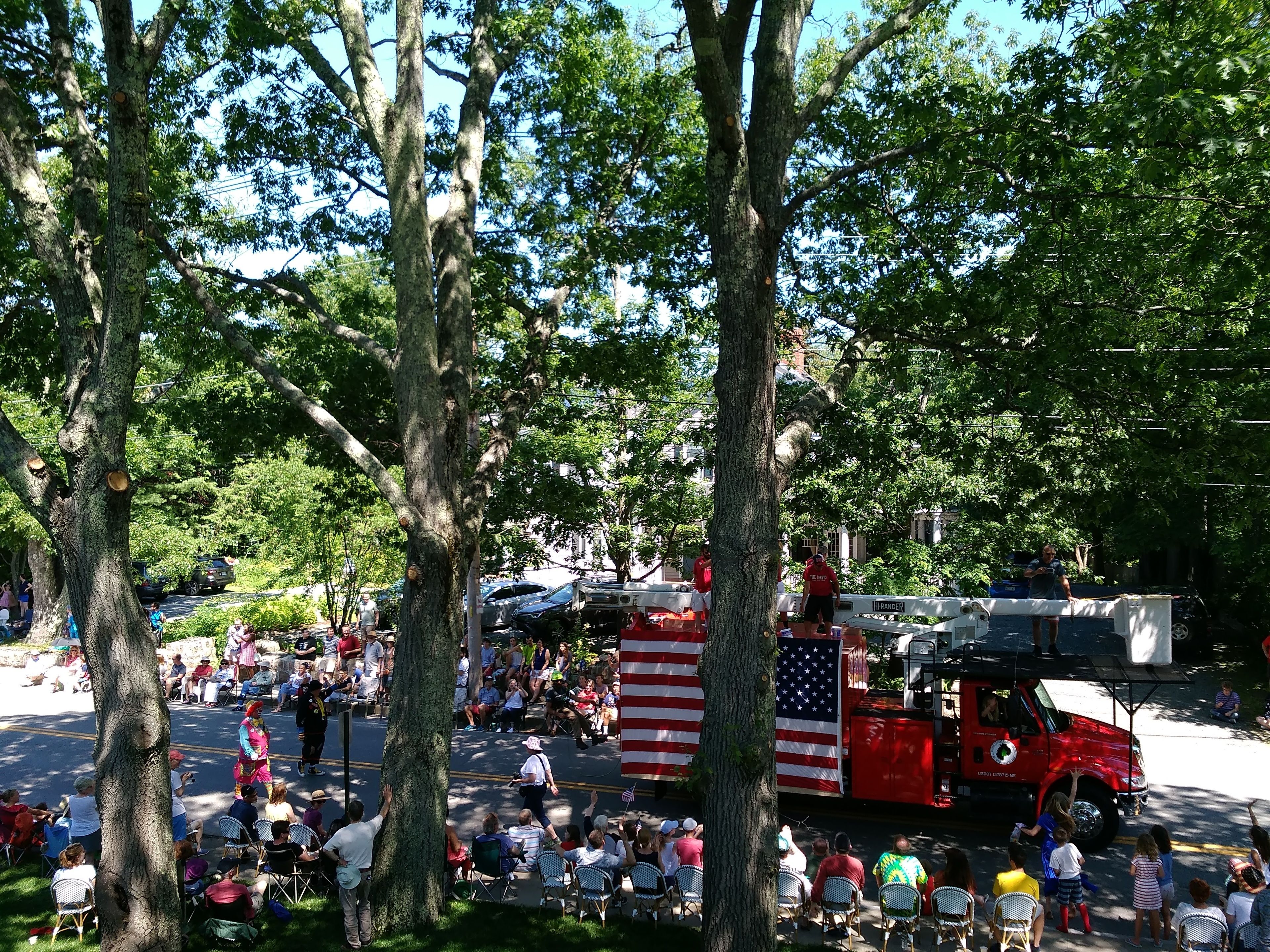 A parade with spectators seated on chairs, a red fire truck, and an American flag.