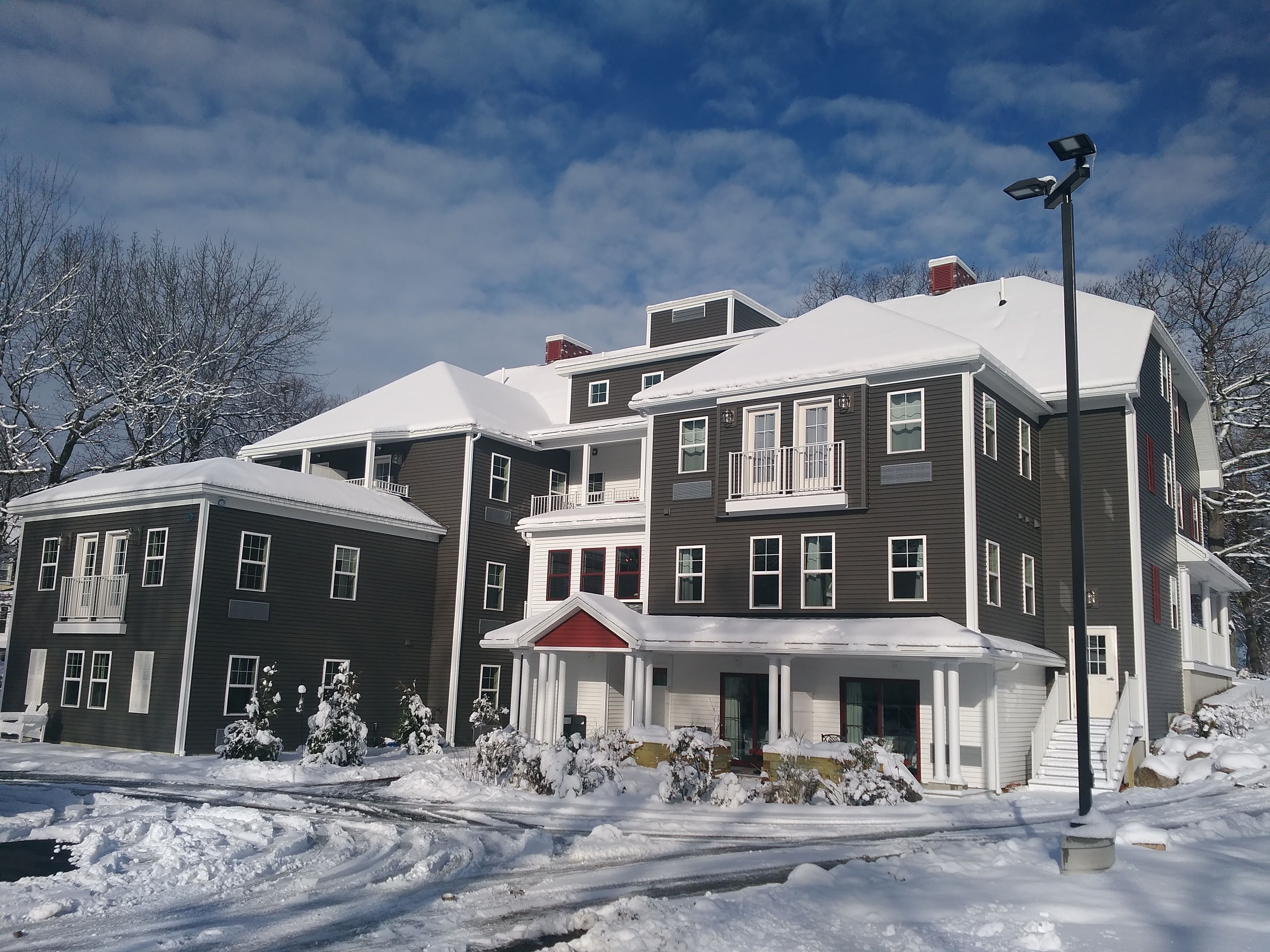 A multi-story residential building with a covered porch and a red roof.