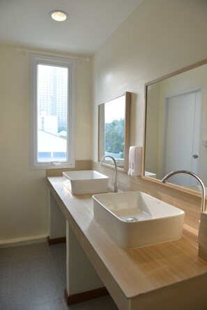 Une salle de bain moderne avec deux lavabos, un grand miroir et une fenêtre qui laisse entrer la lumière naturelle.