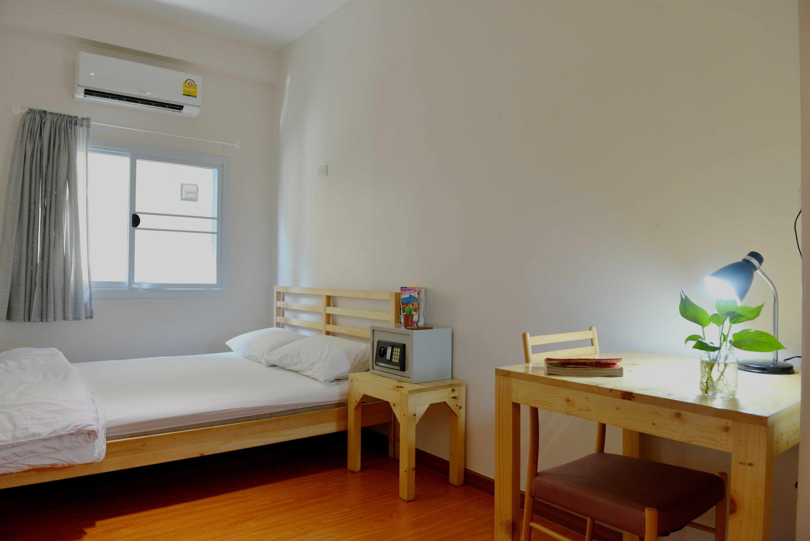 Una habitación con cama, escritorio, silla, lámpara y ventana.