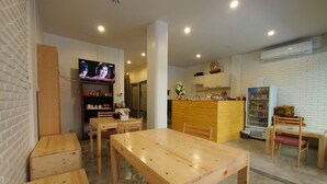 Ein gemütliches Restaurant mit Holztischen und -stühlen, einer Theke mit Getränkespender und einem Fernseher, der ein Programm zeigt.