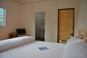 Une chambre d’hôtel avec un lit, une télévision, un ours en peluche, un livre et une porte en bois.