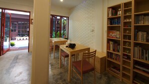 Ein Zimmer mit Esstisch und Stühlen, einem Bücherregal und einer weißen Ziegelwand.