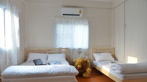 Ein Zimmer mit zwei Holzbettgestellen, einem Teddybären und einer Klimaanlage.
