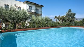 En sÀsongsöppen utomhuspool, parasoller och solstolar