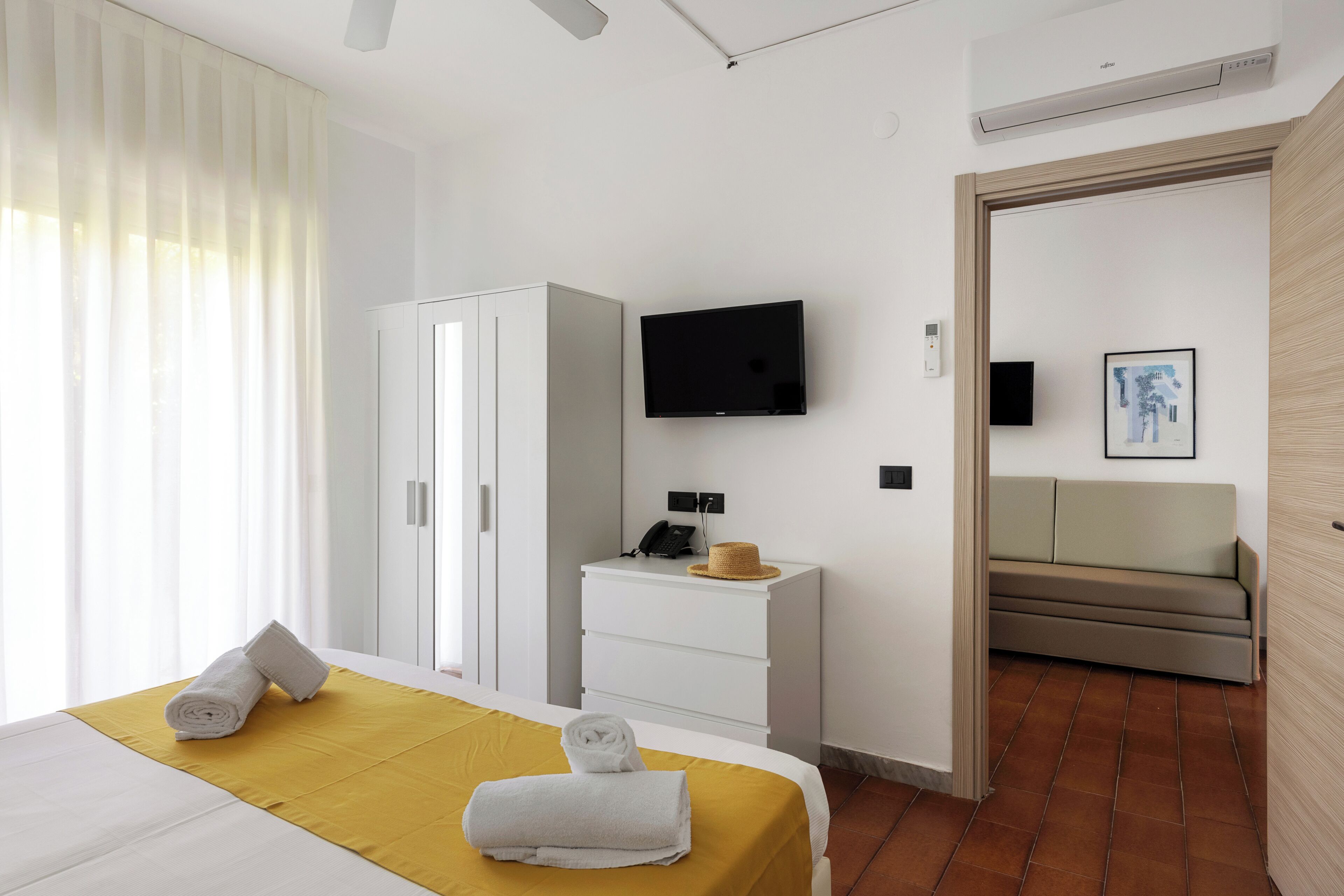 Een hotelkamer met een bed, een televisie, een bureau, een kledingkast en een bank.