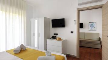 Een hotelkamer met een bed, een televisie, een bureau, een kledingkast en een bank.