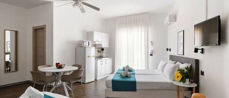 A hotel room with two beds, a desk, a chair, a TV, and a ceiling fan.