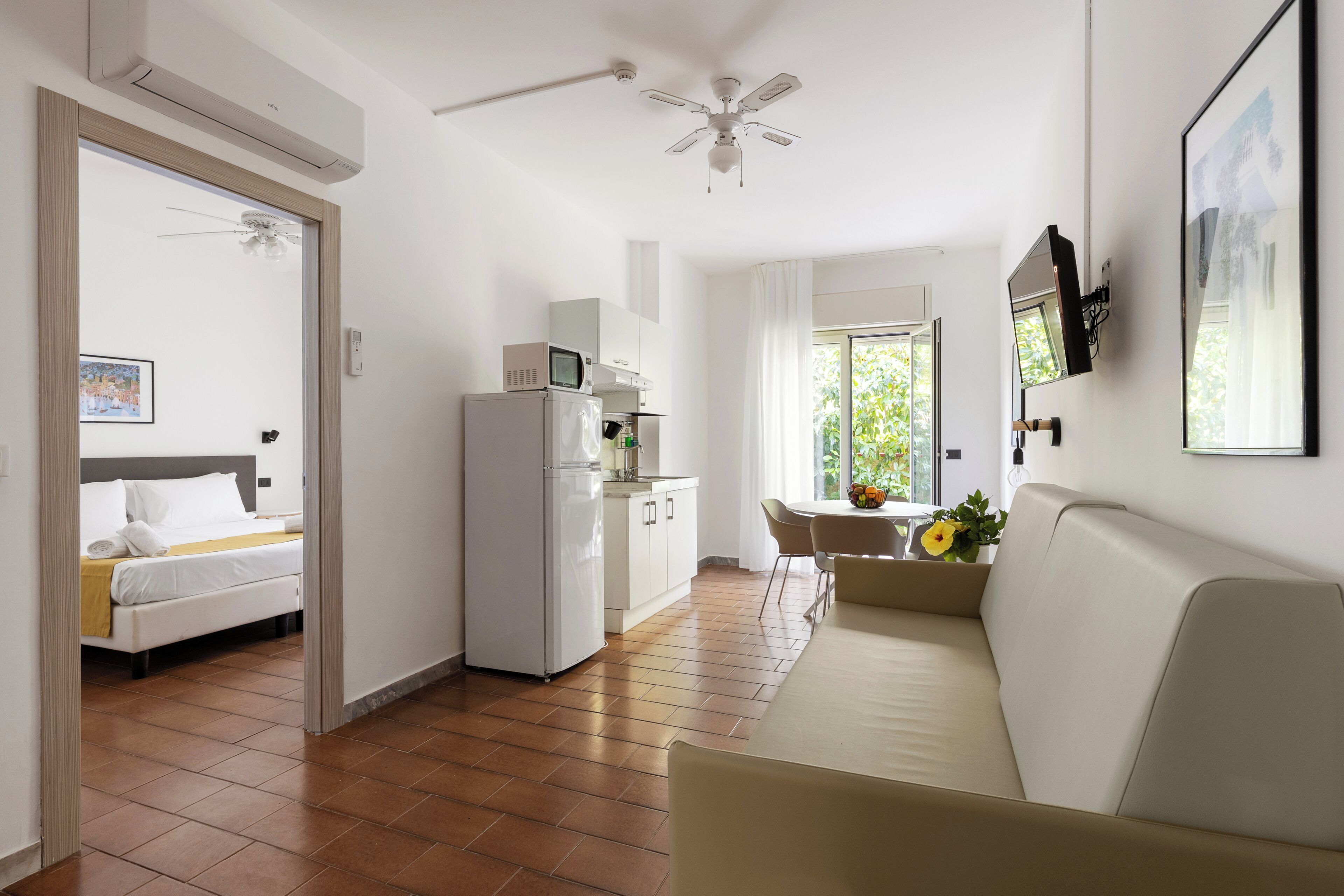 Una habitación de hotel con cama, kitchenette, sofá y ventilador de techo.