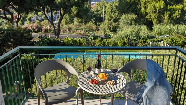 A balcony with a table set for two, a bottle of wine, and a basket of fruit. - Villa Collina (Giardini Naxos)