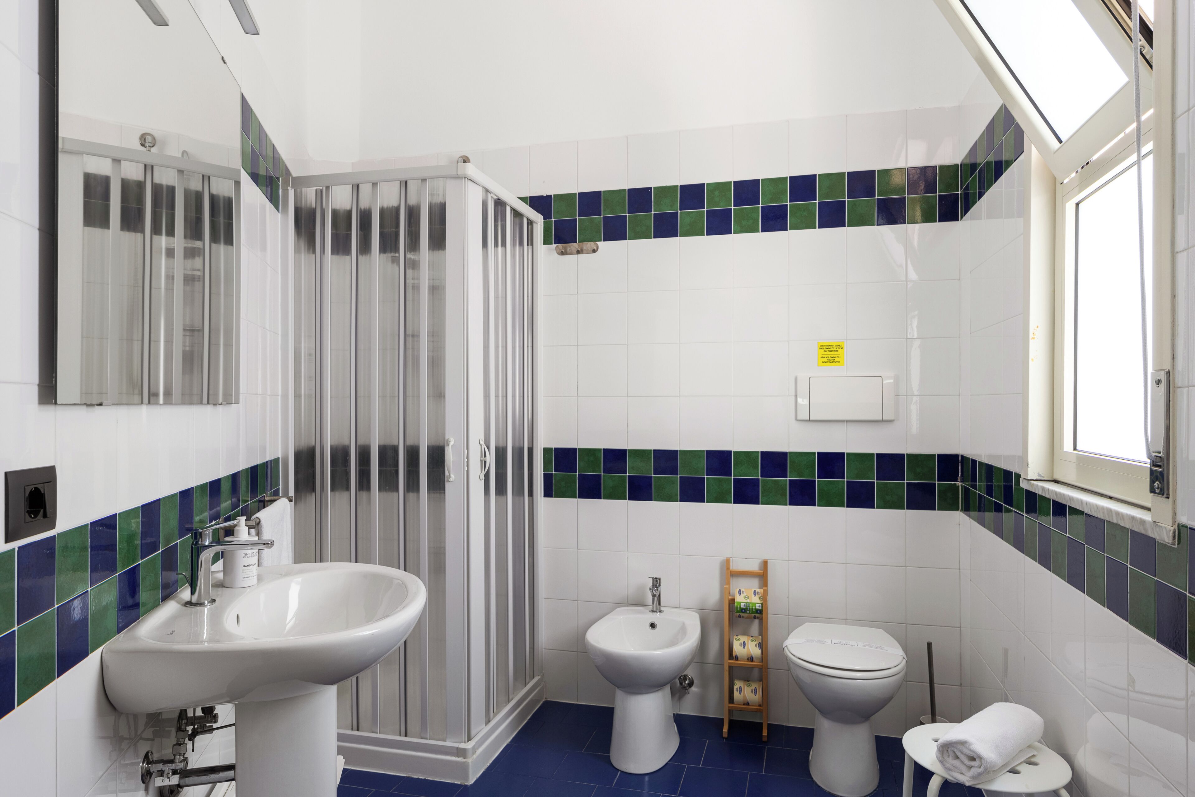 Un bagno con doccia, lavandino, bidet, WC e porta asciugamani.