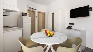 A compact kitchen with a microwave, a small refrigerator, and a dining area with a round table and two chairs. - Villa Collina (Giardini Naxos)