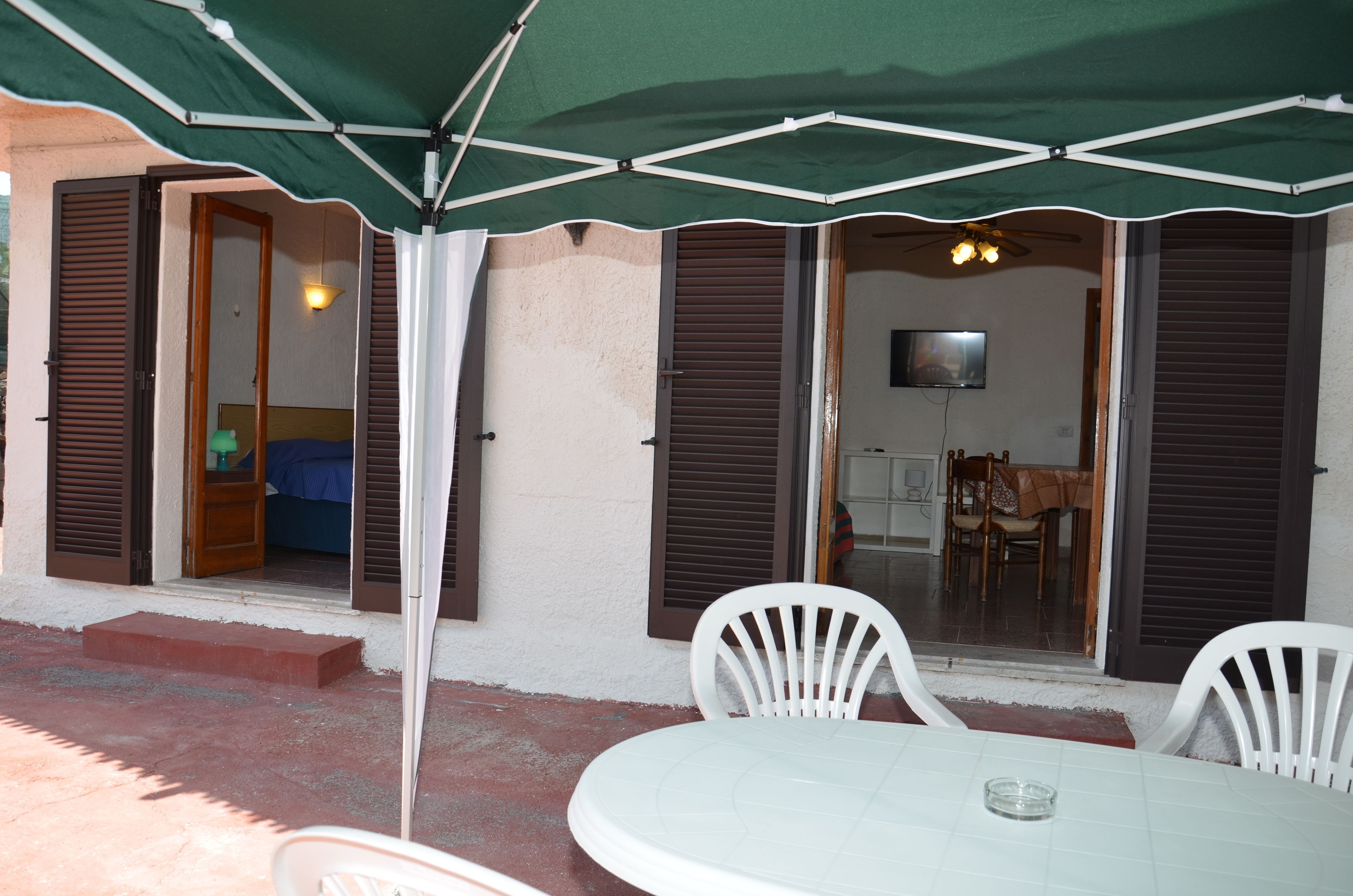 Un'area patio con tavolo e sedie, una ventola a soffitto e una televisione sullo sfondo.