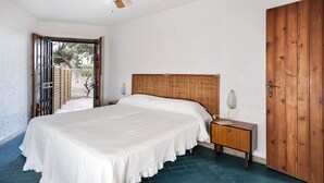 A bedroom with a bed, wooden headboard, bedside table, and a ceiling fan. - Residence Villa Liliana (Giardini Naxos)
