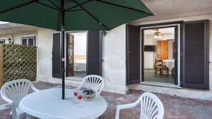 A patio with a table, chairs, and a green umbrella. - Residence Villa Liliana (Giardini Naxos)