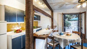 A kitchen with wooden cabinets, a dining table set with a teapot, cups, and a plate of food. - Residence Villa Liliana (Giardini Naxos)