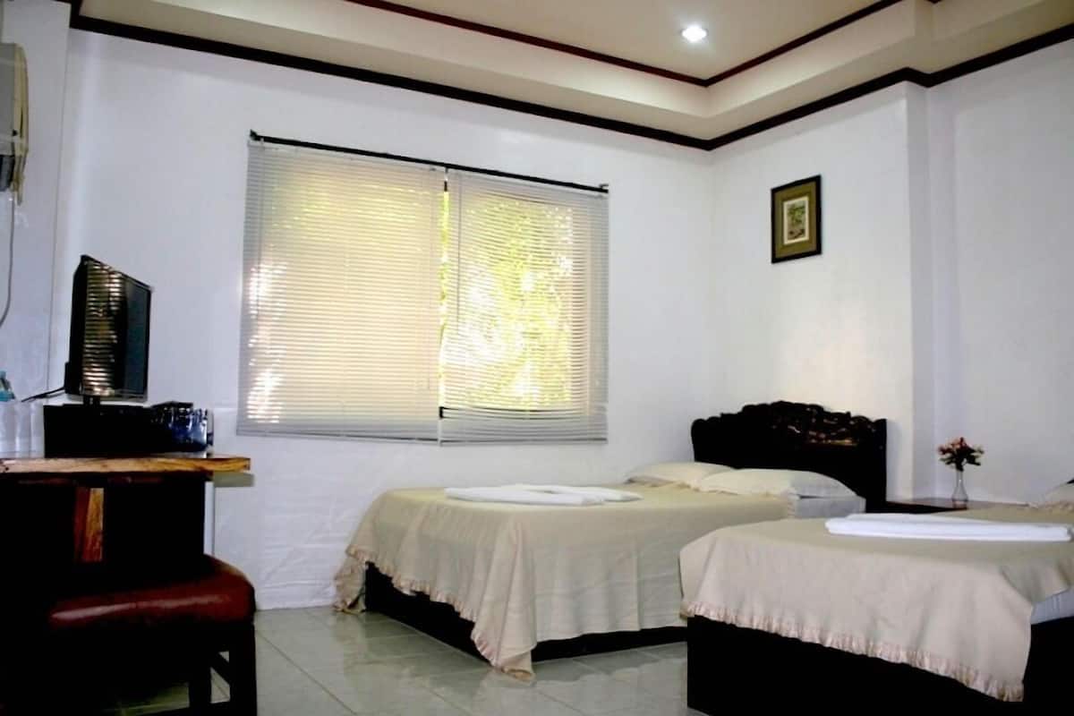 A bedroom with two beds, a desk, and a window with blinds.