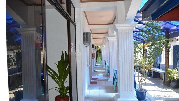 A corridor with white columns, potted plants, and a blue canopy. - Island Inn Boracay (Boracay Island)