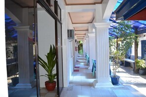 A corridor with white columns, potted plants, and a blue canopy. - Island Inn Boracay (Boracay Island)