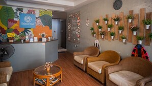 A reception area with wicker chairs, a reception desk, a clock, and a wall decorated with potted plants. - Island Inn Boracay (Boracay Island)