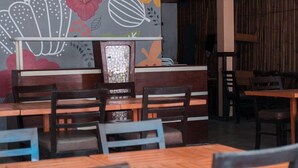 A restaurant interior with wooden tables and chairs, a decorative wall with floral patterns, and a bamboo backdrop. - Island Inn Boracay (Boracay Island)