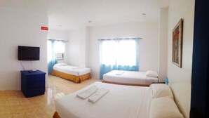 A hotel room with a bed, a TV, a desk, and a window with curtains. - Island Inn Boracay (Boracay Island)