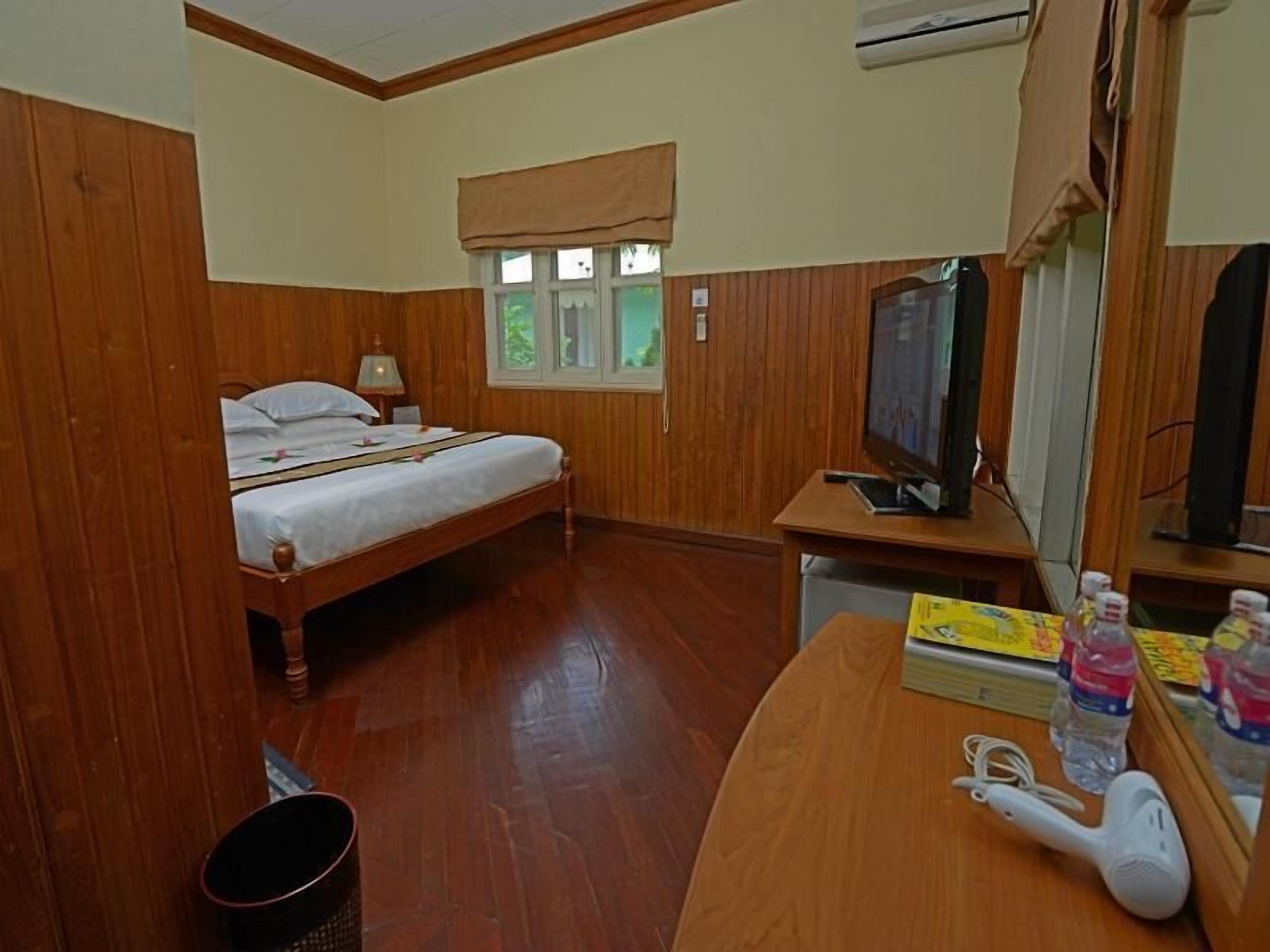 Una habitación con cama, un escritorio con espejo, televisión y secador de pelo.
