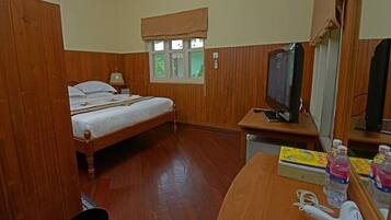 Una habitación con cama, un escritorio con espejo, televisión y secador de pelo.