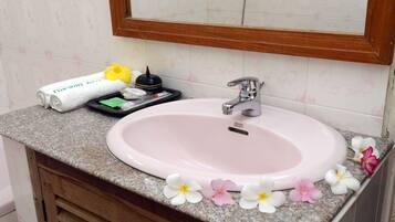 A bathroom sink with a wooden vanity, a mirror above it, and a towel with a hotel name on it.