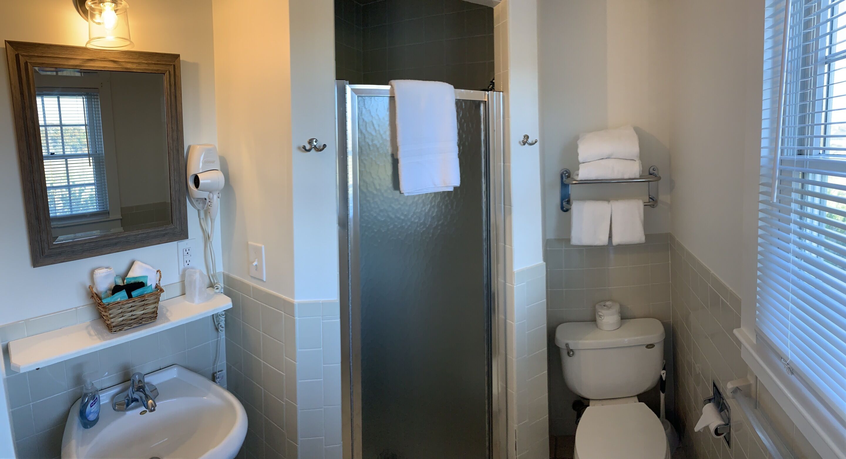 Un baño con ducha, inodoro, lavabo y toallero.