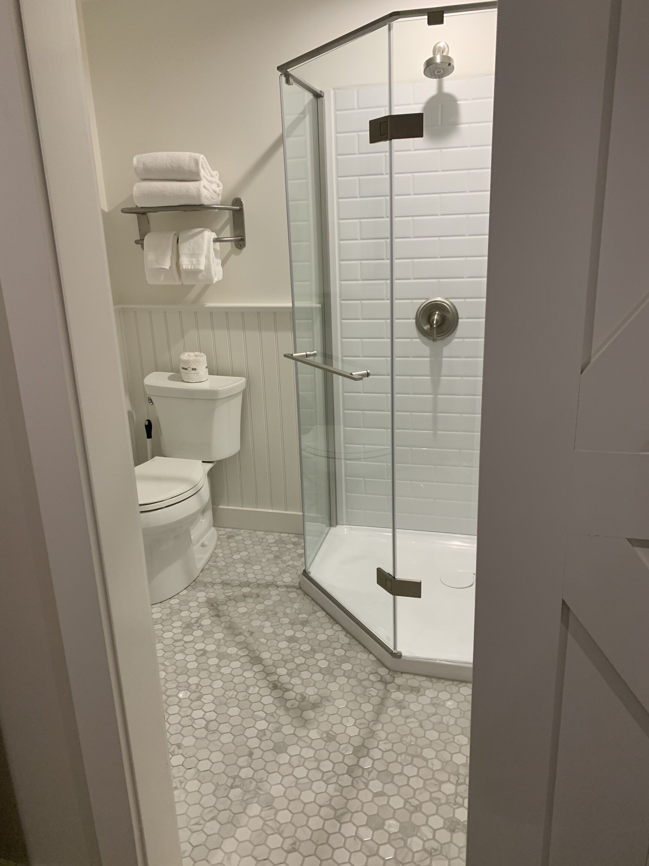 A bathroom with a glass-enclosed shower, a toilet, and a sink.