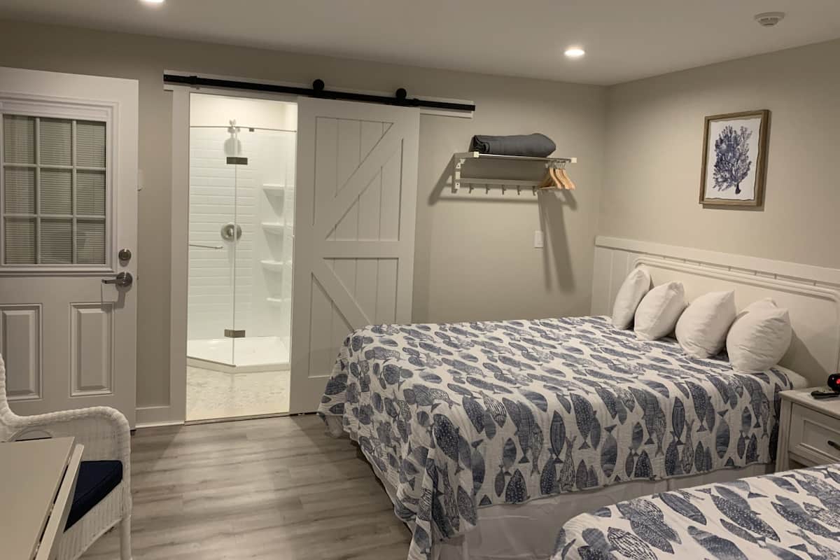 A bedroom with a bed, a chair, a wardrobe, and a door leading to a bathroom.